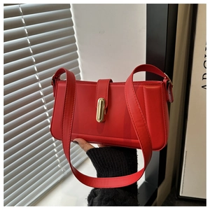 Détail d'un sac sous le bras en cuir rouge avec un fermoir rotatif en métal doré