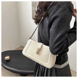 Detail view of cream square shoulder bag with gold metal buckle on female model back