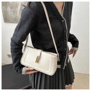 Close-up of minimalist cream square shoulder bag with gold metal clasp on model