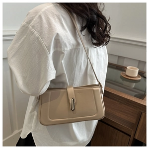 Detail of beige shoulder bag featuring rectangular stitching and gold metal buckle clasp