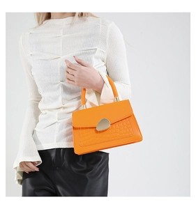 Detail of orange crocodile embossed PU leather handbag with pebble-shaped gold metal clasp