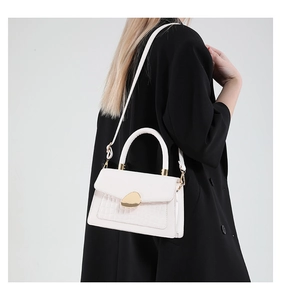 Detail of crocodile pattern PU bag featuring a minimalist gold pebble-shaped buckle