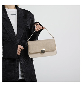 Détail d'un sac crème tissé doté d'une grande boucle métallique magnétique ronde dorée