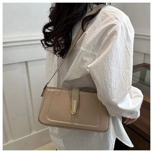 Close-up of beige crossbody bag with premium gold metal clasp and minimalist stitching