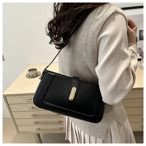 Detail of minimalist black underarm bag with gold metal buckle on a shoulder strap