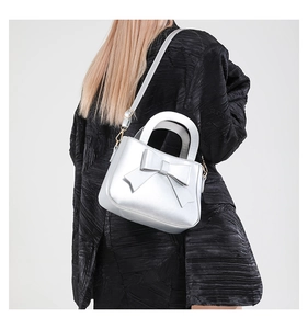 Close-up of a metallic silver bow handbag with gold hardware and smooth pearl finish