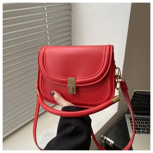 Detail view of red leather crossbody bag with gold rectangular metal clasp and fine stitching