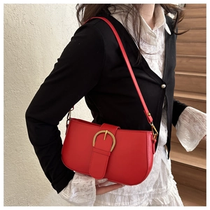 Détail d'un sac à bandoulière en cuir rouge avec boucle dorée porté par un mannequin