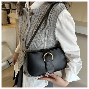 Détail du sac bandoulière vintage en cuir noir avec boucle dorée en fer à cheval