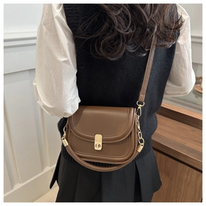 Detail of vintage caramel saddle bag with gold buckle on crossbody model