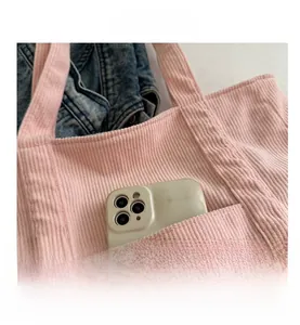 Detail of pink corduroy tote bag featuring a practical exterior pocket for a smartphone