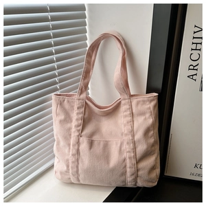 Detail of light pink corduroy tote bag showing soft ribbed texture and front pocket design