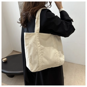 Detail of cream corduroy tote bag with front pocket showing vertical ribbed texture