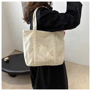 Detailed texture of white corduroy tote bag showing large capacity and side pocket feature