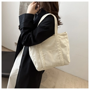 Detail of off-white corduroy tote bag featuring vertical ribbed texture and side pocket