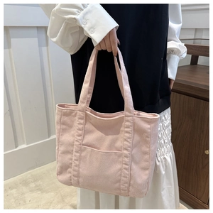 Close-up of pink corduroy tote bag featuring thick ribbed texture and front patch pocket