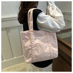 Side view of a light pink corduroy tote bag showing its texture and capacity on a model
