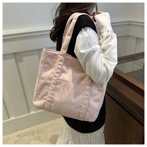 Detail of soft pink corduroy tote bag showing fine ribbed texture and front pocket