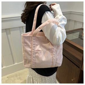 Detail of pink corduroy tote bag showing vertical rib texture and front patch pocket