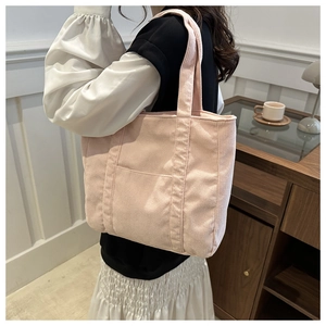 Close-up of pink corduroy tote bag texture showing vertical ribbing and front pocket