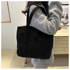 Detail of black corduroy tote bag showing textured ribbed fabric and front pocket