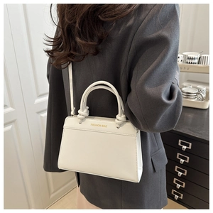 Detail of white leather handbag featuring knotted handle and gold fashion bag logo print