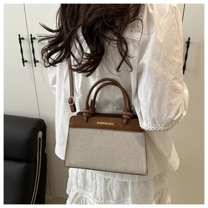 Detail shot of the woven texture and contrast stitching on a brown leather crossbody bag