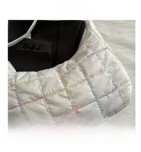 Close-up of quilted puffy shoulder bag with rainbow contrast stitching on white fabric