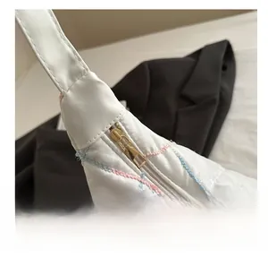 Detailed macro of smooth gold metal zipper and colorful diamond stitching on white tote bag