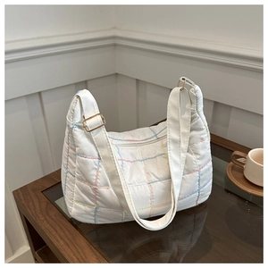 Detail of white quilted tote bag featuring colorful grid stitching and adjustable gold buckle