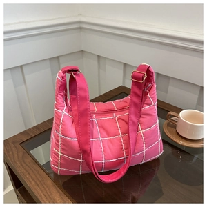 Detail of rose red quilted shoulder bag with white stitching and golden metal buckle