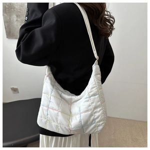 White quilted hobo bag with colorful grid stitching shown on shoulder by a model