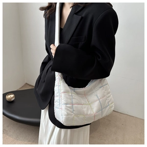Detailed shot of white quilted tote bag with colorful grid stitching worn on shoulder