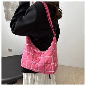 Detailed back view of a woman wearing a pink quilted nylon tote bag with white stitching