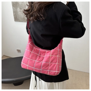 Detail of pink quilted shoulder bag with white grid stitching on puffy nylon material