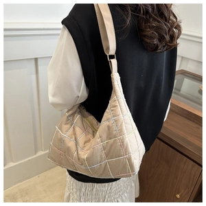 Detail of beige quilted hobo bag with colorful stitching and soft cloud-like texture