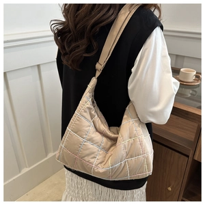 Detail of beige tote bag featuring colorful quilted grid lines and adjustable strap