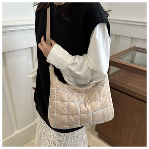 Detail of beige quilted crossbody bag with colorful stitching and adjustable strap