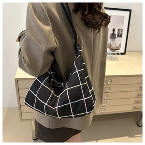 Lifestyle shot of a black plaid tote bag with colorful grid patterns and leather straps
