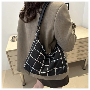 Close-up of quilted black nylon hobo bag with colorful grid stitching and adjustable strap