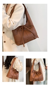 Detail of a brown hobo shoulder bag with a bow knot and heart-shaped metal ornament