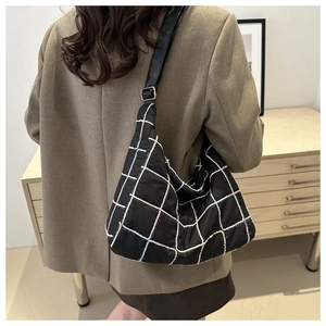 Detail of colorful plaid quilted shoulder bag with black strap and golden buckle