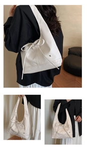 Detail of cream tote bag with large bow and heart-shaped metal buckle attachment