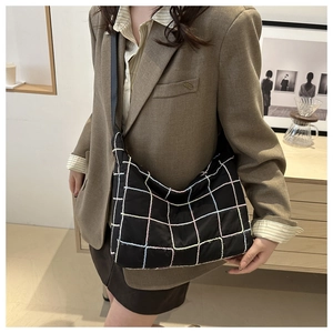 Detail of black large capacity tote bag with colorful grid patterns on shoulder
