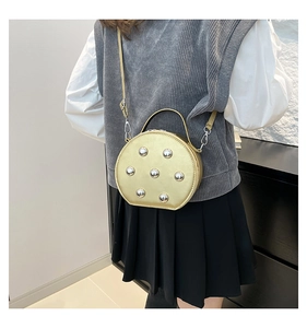 Détail du sac demi-lune doré métallisé avec rivets argentés porté à l'épaule
