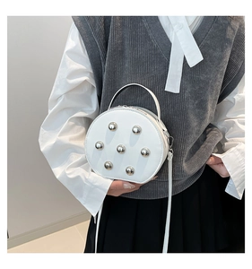 Détail du sac rond blanc à bandoulière avec clous argentés et lanière en cuir