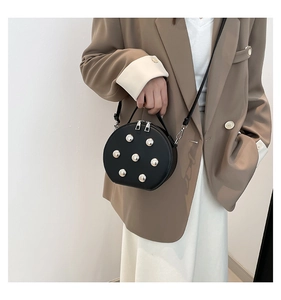 Gros plan d'un mini sac bandoulière rond noir avec clous argentés sur un mannequin