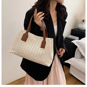 Detail of hand-woven straw tote with brown leather handles in a modern home setting