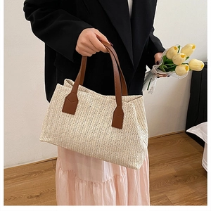 Detail of hand-woven beige straw tote bag with brown leather handles for summer