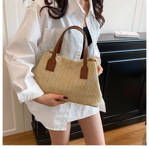 Detailed close-up of woven straw texture and premium brown leather handles on a tote bag